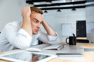 Angry desperate young businessman sitting at the table